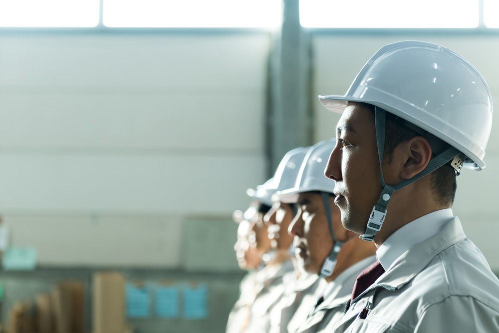 ヘルメットをかぶり作業服を着た作業員が複数名並んでいる様子